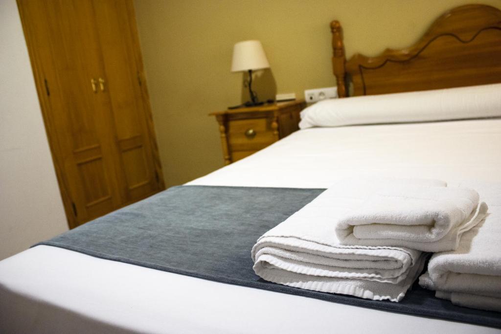 Hostal Valdepeñas by Bossh Hotels في فالديبينياس: غرفة نوم عليها سرير وفوط بيضاء