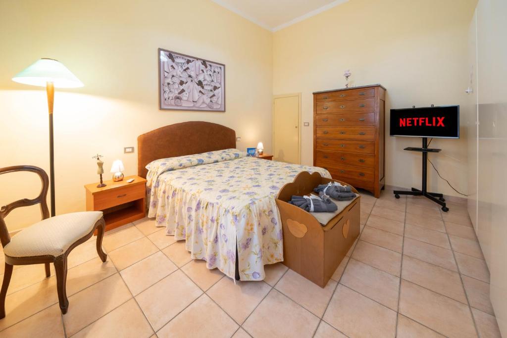 een slaapkamer met een bed, een dressoir en een stoel bij [NEL CUORE DELLA CITTADINA TERMALE] MAISON M&V in Montecatini Terme