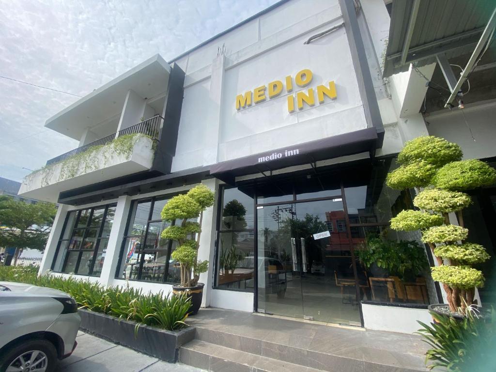 una señal de la posada en la parte delantera de un edificio en Urbanview Hotel Medio Inn Palu by RedDoorz en Palu