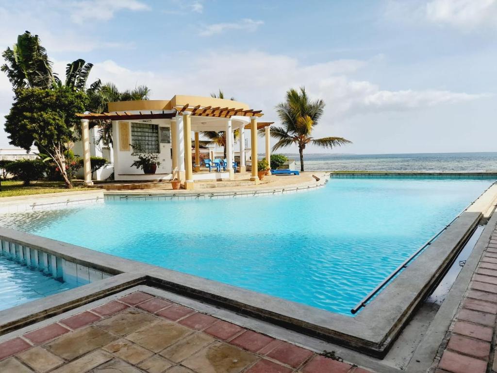 Perfect sea view 2 في مومباسا: حمام سباحة مع شرفة بجوار المحيط
