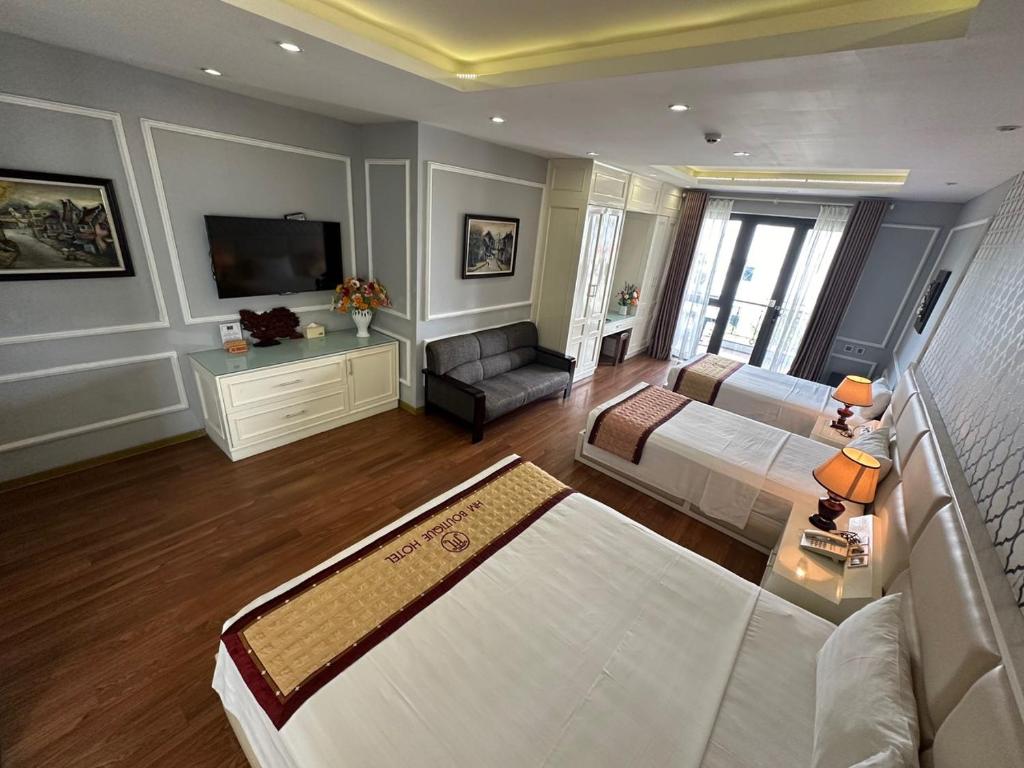 a large room with two beds and a couch and a television at Hanoi HM Boutique Hotel in Hanoi