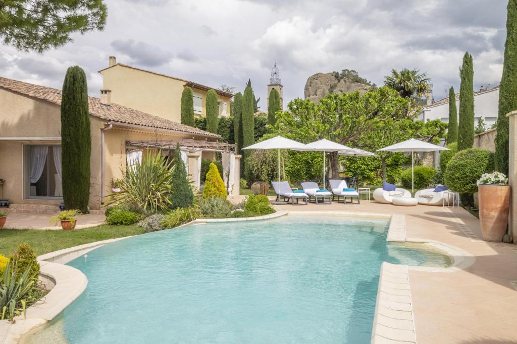 una piscina en un patio con sillas y sombrillas en Villa Ambre, en Digne-les-Bains