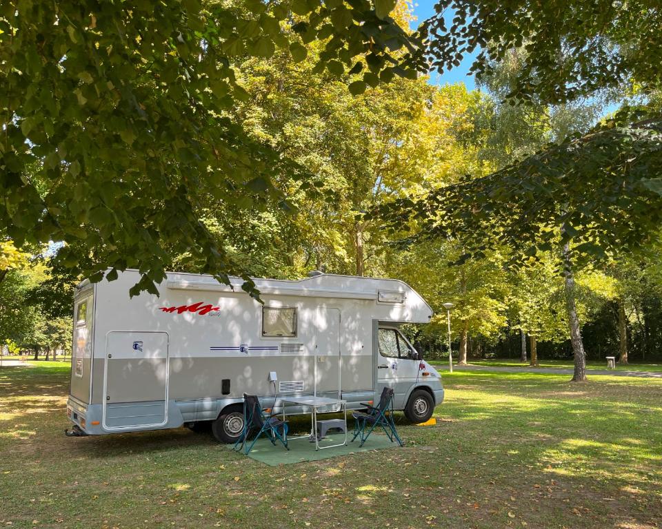 a white caravan parked in a park under a tree at Thermal Camping Zalakaros in Zalakaros