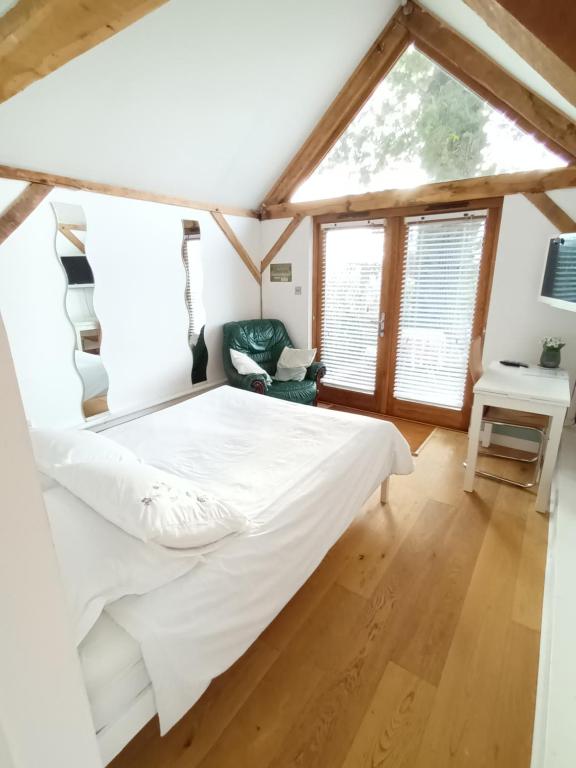 a bedroom with a large bed and a window at Little Oak - Double (Kingsize) Self Contained Oak Studio - Sleeps 2 in Chiddingfold