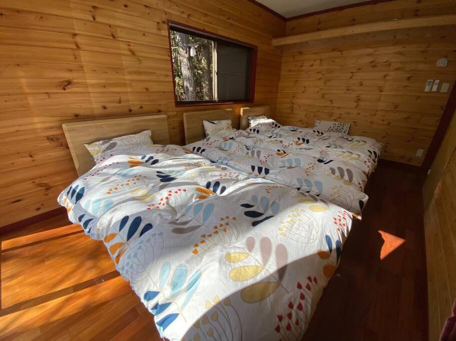 two beds in a room with wooden walls at 森の中のぽつんとワンワン別荘 in Nikko