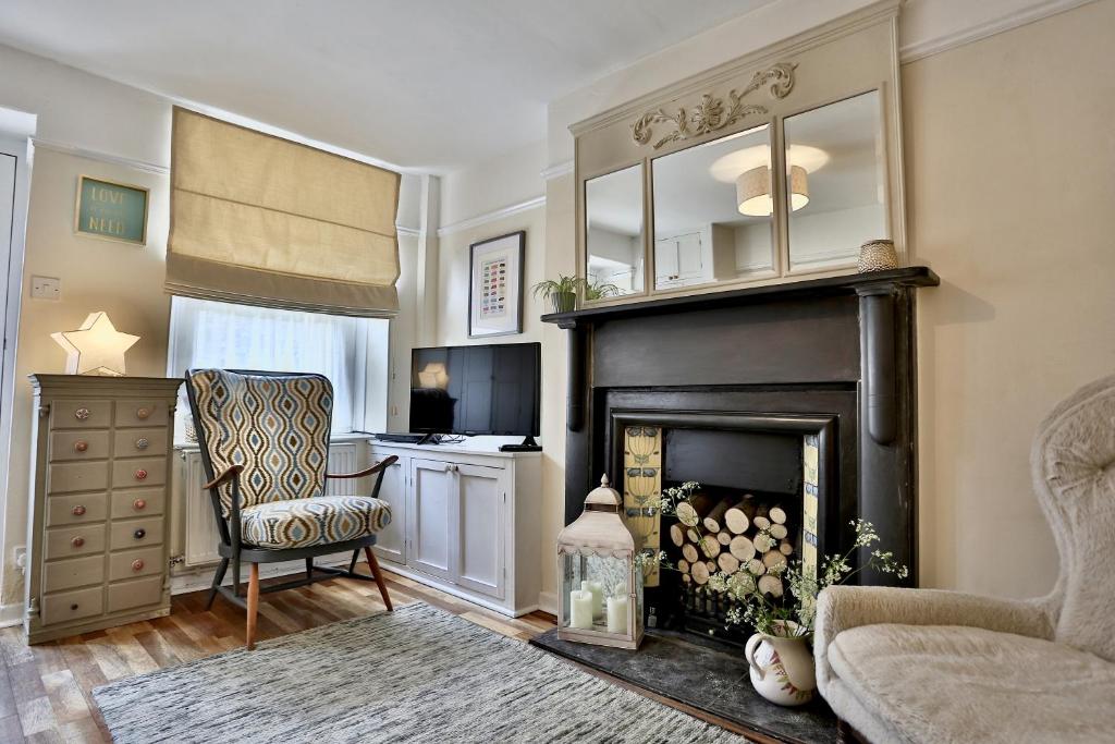 a living room with a fireplace and a chair at Caboodles Cottage in Crickhowell