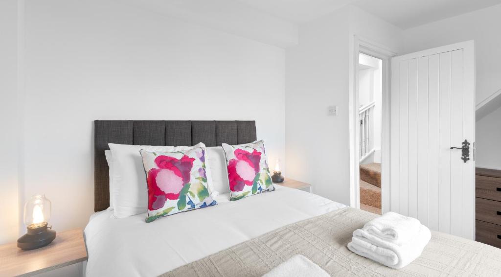 ein weißes Schlafzimmer mit einem Bett mit rosa Blumen drauf in der Unterkunft Well Coach House by Cliftonvalley Apartments in Bristol