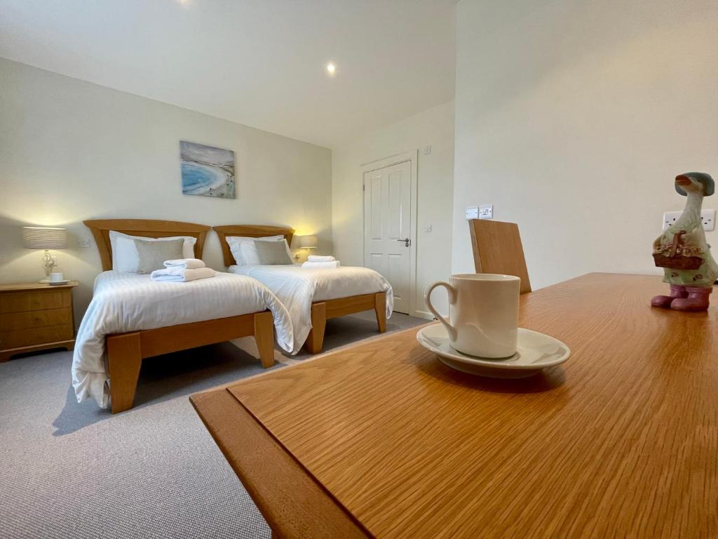a bedroom with two beds and a table with a cup on it at Cosy room with golf & the beach on your doorstep! in Mawgan Porth