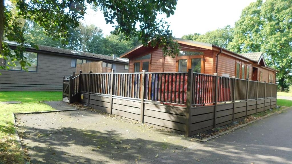 a house with a wooden fence in front of it at The Lodge, Alder Country Park in North Walsham