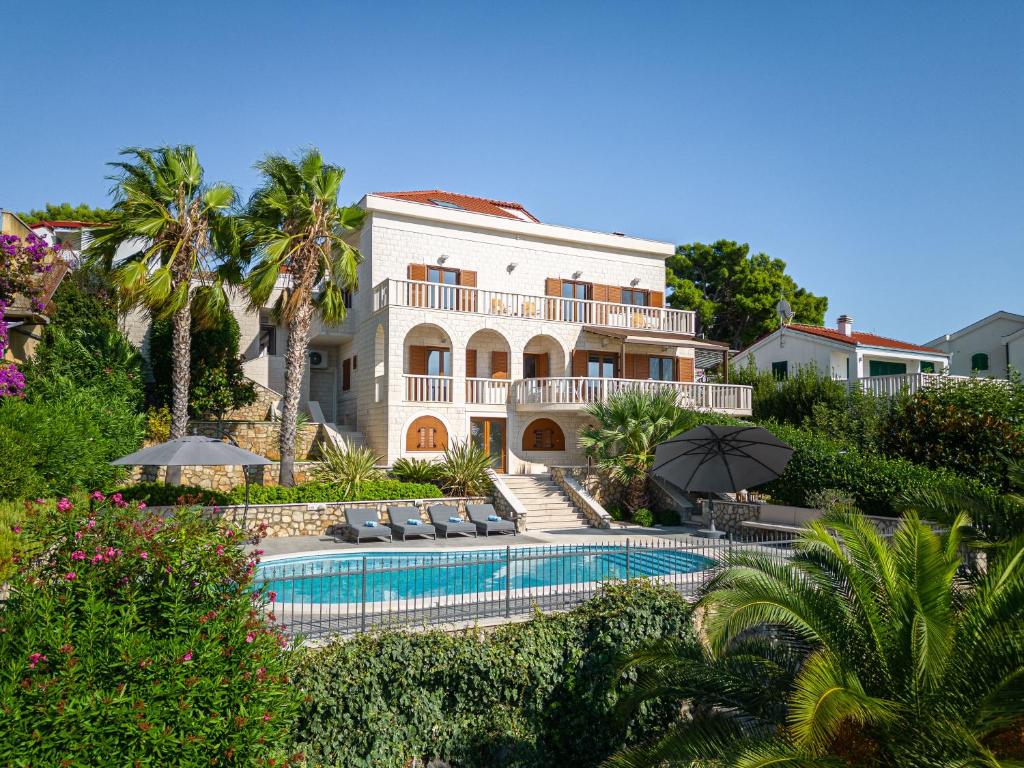 a large house with a swimming pool in front of it at Luxury Sunset Villa Trogir Private Beach in Okrug Donji