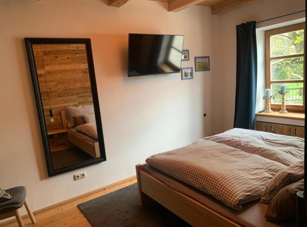 1 dormitorio con cama, espejo y silla en Moarhof Ferienwohnung1 en Dietramszell