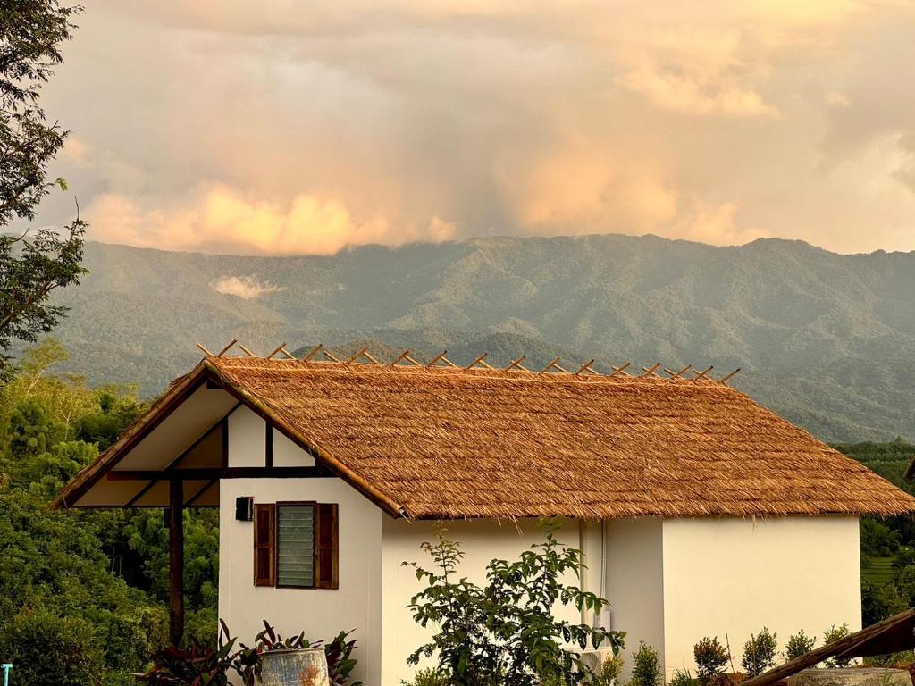 a white house with a roof with mountains in the background at Utopua Resort ยูโทปัวว์ รีสอร์ท in Pua