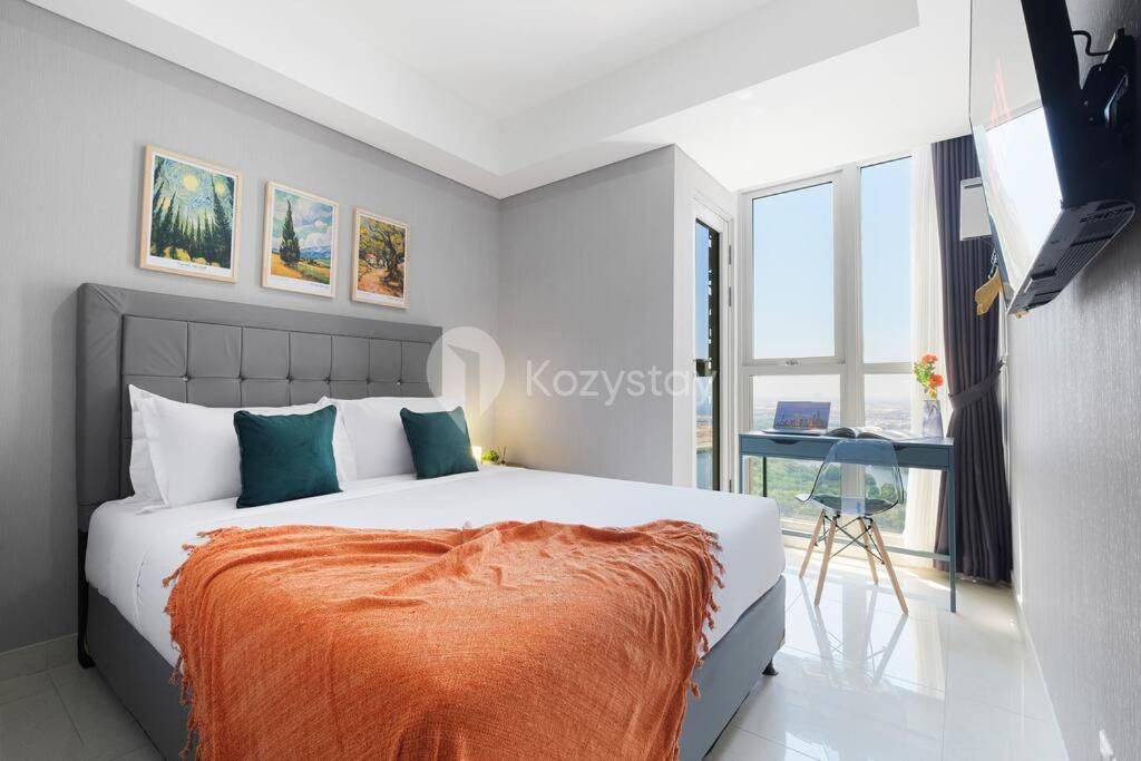 una camera da letto con un letto con una coperta arancione sopra di Sonrisa by Kozystay - Studio - Ocean View - PIK a Giacarta