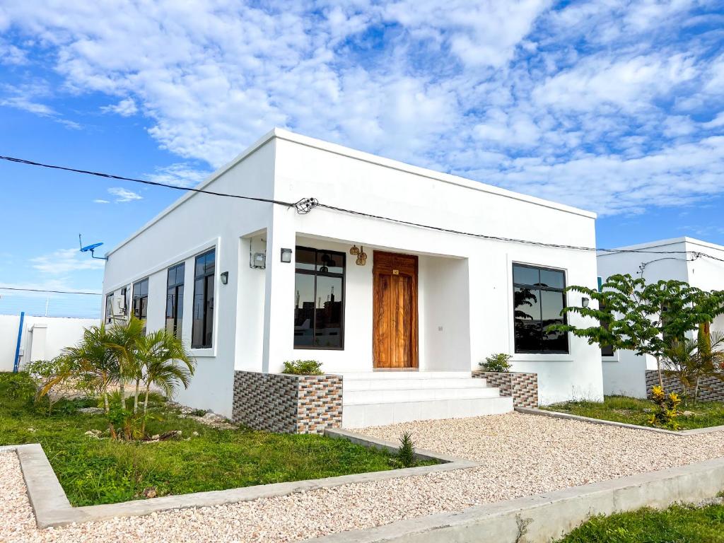 una casa bianca con una porta rossa di Kijiji Villas Nungwi a Banda Kuu