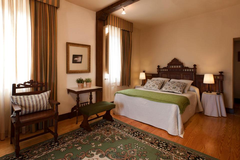 a bedroom with a large bed and a chair at Hotel Villa Miramar in poo de Llanes