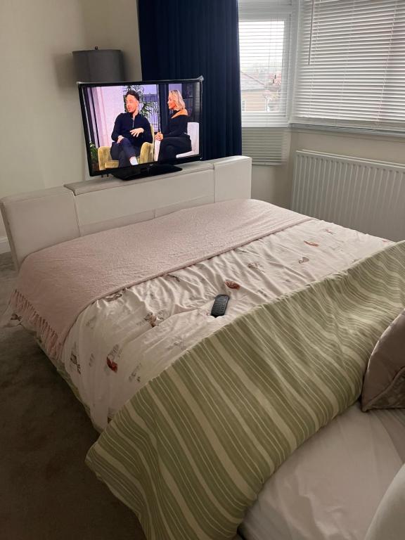 - une chambre avec un lit et une télévision murale dans l'établissement Home from Home Cosy B&B, à Londres