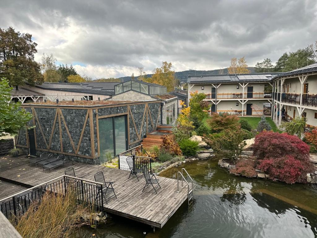 una casa con terrazza in legno accanto a un fiume di Penzión & Wellness MERIDIANA Bojnice rezort a Bojnice