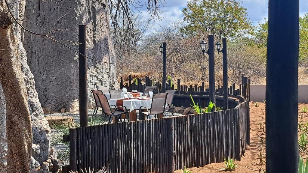 a fence with a table and chairs in a garden at Hambana Lifestyle Lodge in Musina