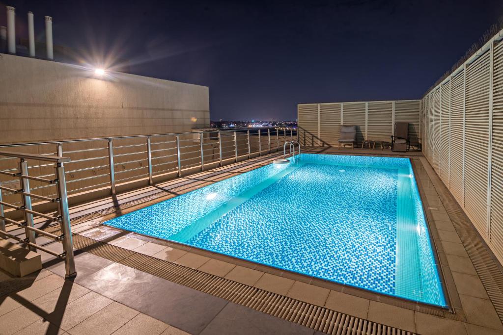 a swimming pool on the roof of a building at night at Jiwar Hotel in Jeddah