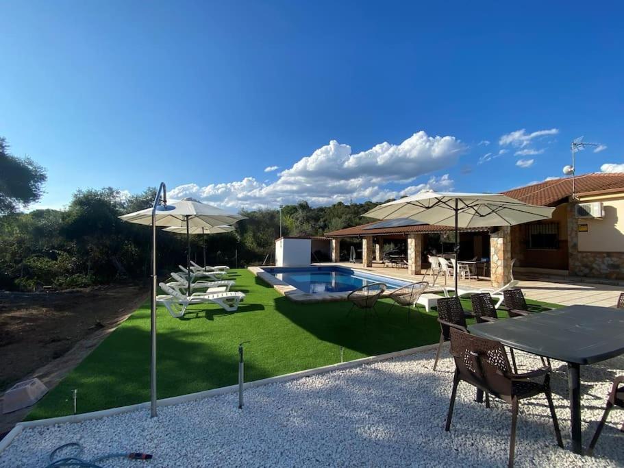 eine Terrasse mit einem Tisch und Sonnenschirmen neben einem Haus in der Unterkunft Casa Rural Il Consigliere in Córdoba