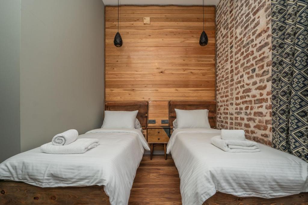 two twin beds in a room with wooden walls at Hotel Piano Kvareli in Kvareli