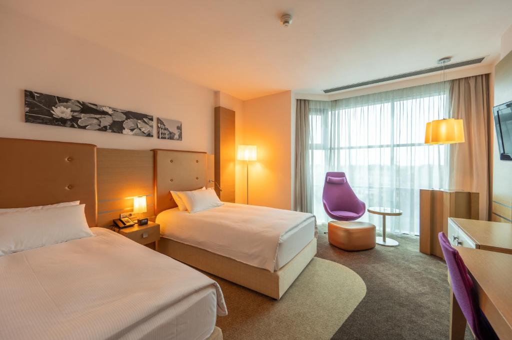 una habitación de hotel con 2 camas y una silla morada en DoubleTree by Hilton Oradea, en Oradea