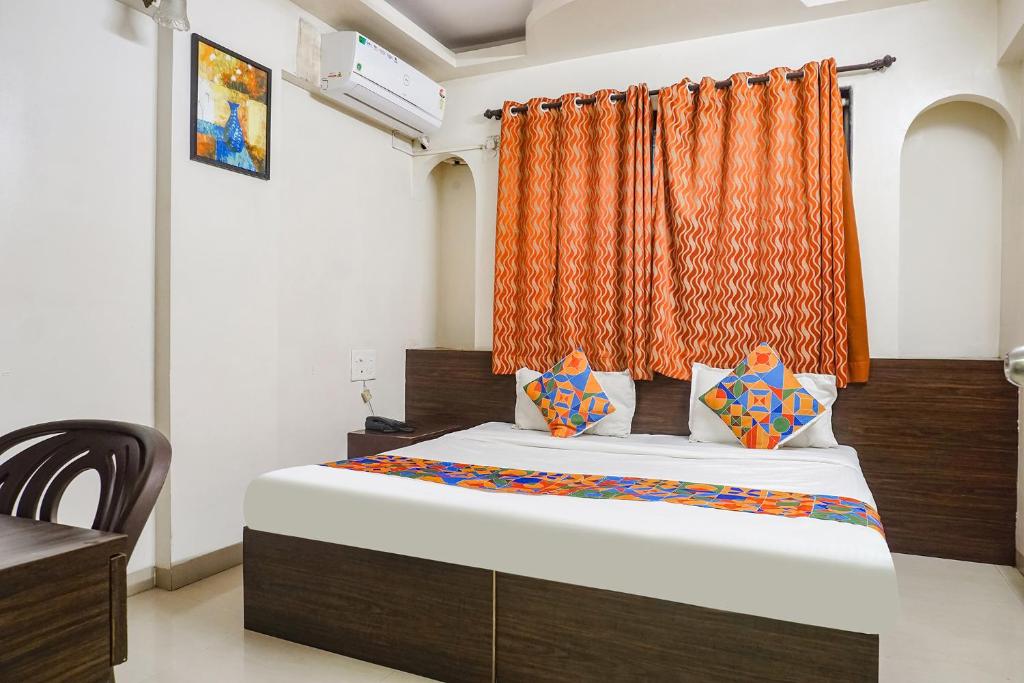um quarto com uma cama com uma cortina laranja em FabHotel Royal Samrat em Pune
