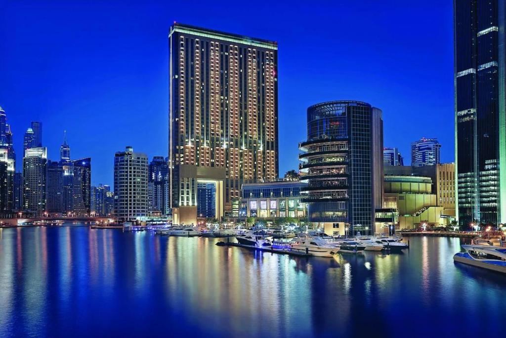 Address Marina Mall Suites "Full Marina Views & Balcony " في دبي: أفق المدينة مع القوارب في الماء في الليل