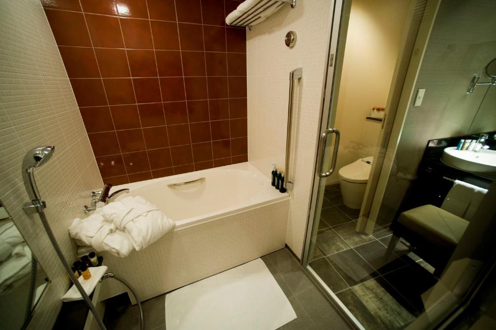 a bathroom with a bath tub and a toilet at ANA Crowne Plaza Kanazawa by IHG in Kanazawa