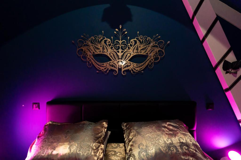 ein Schlafzimmer mit einer goldenen Maske über einem Bett in der Unterkunft L'incognito - Romantisme - Vin - Jacuzzi in Saumur