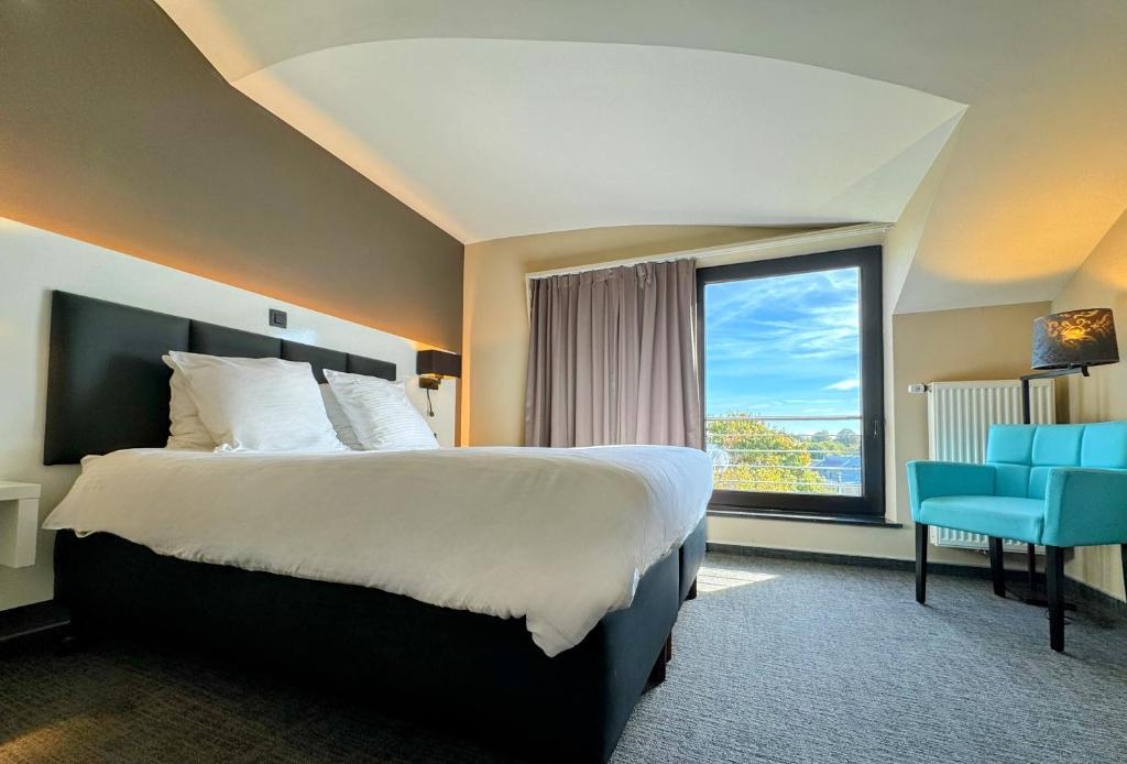 um quarto de hotel com uma cama e uma grande janela em Hôtel L'Amandier em Libramont