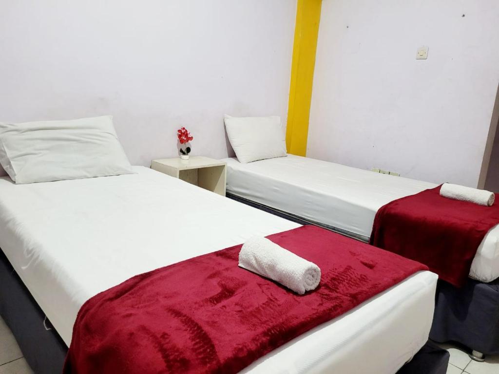 2 camas en una habitación con sábanas rojas y blancas en Wisma Gahalta by Fans en Karawang