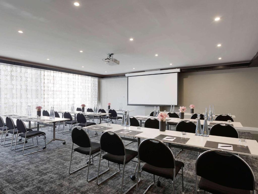 a conference room with tables and chairs and a projection screen at Mövenpick Hotel Auckland in Auckland