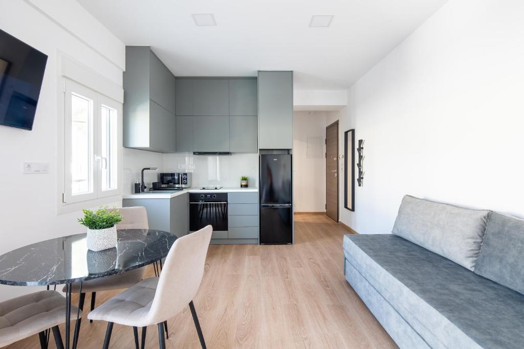 een keuken en een woonkamer met een tafel en een bank bij Boutique Studios near Airport in Pallíni