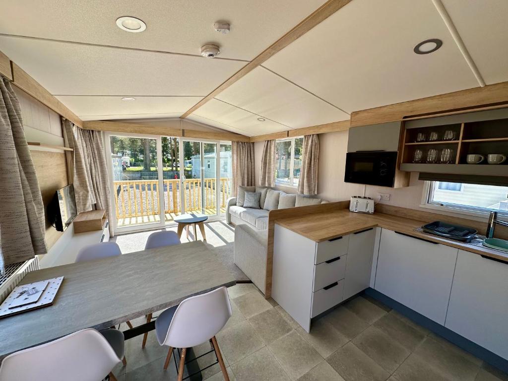a caravan kitchen and living room with a table and chairs at The Ghillie's Van - Beautiful, luxury static caravan in Aberlour