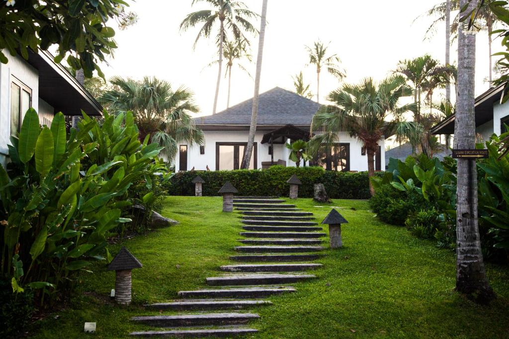 a house with stairs leading to a yard with palm trees at The Racha in Ko Racha Yai 