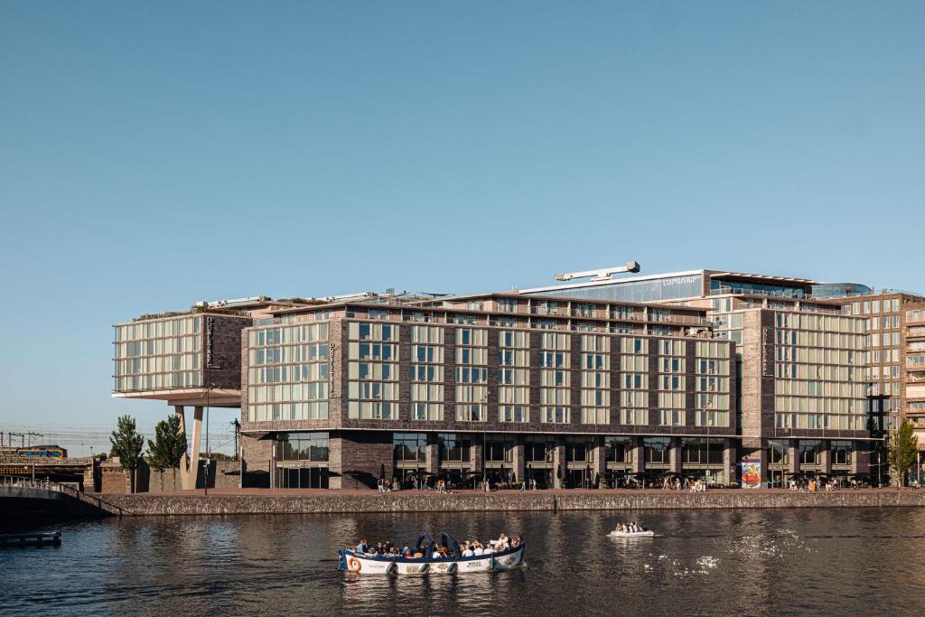 eine Gruppe von Menschen in einem Boot in einem Fluss mit einem Gebäude in der Unterkunft DoubleTree by Hilton Amsterdam Centraal Station in Amsterdam