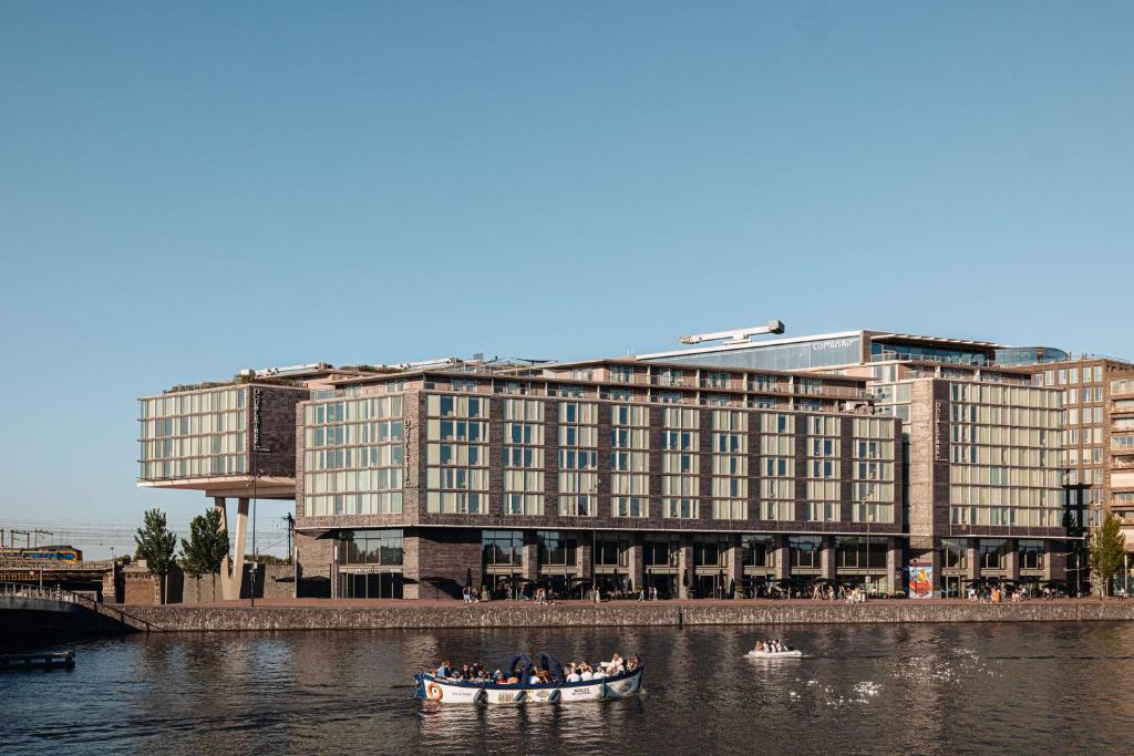 um grupo de pessoas em um barco em um rio com um edifício em DoubleTree by Hilton Amsterdam Centraal Station em Amsterdã