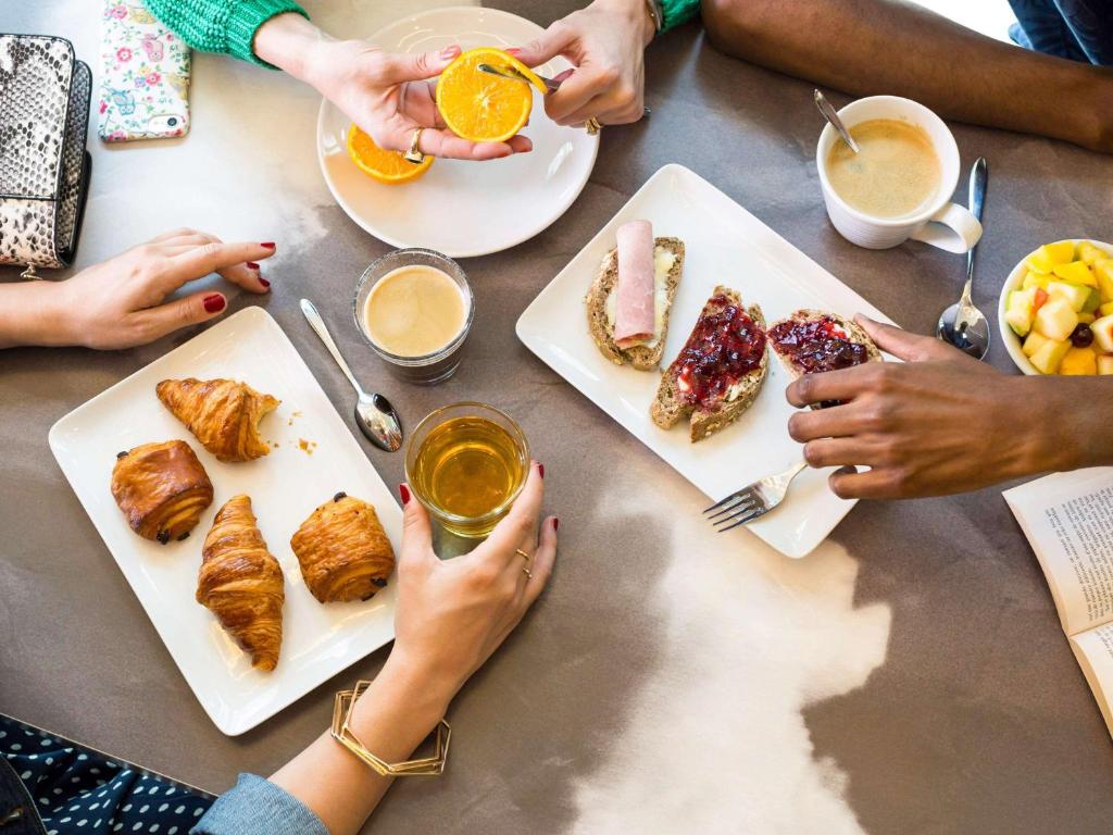 a group of people sitting around a table eating breakfast at ibis Styles Paris Charles de Gaulle Airport in Roissy-en-France