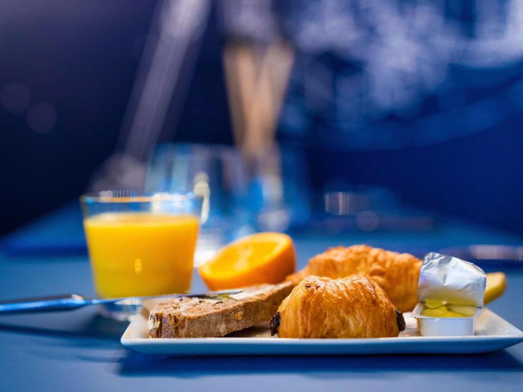 a plate of breakfast food and orange juice on a table at ibis Styles Paris Charles de Gaulle Airport in Roissy-en-France