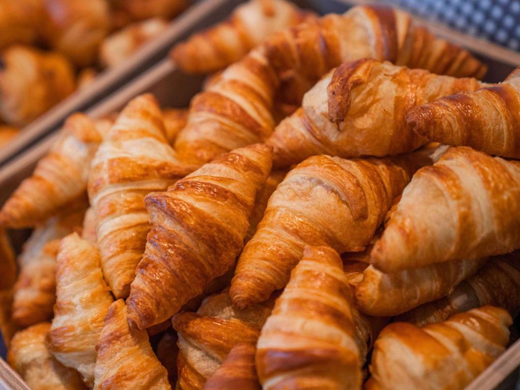 a pile of croissants and other pastries in a tray at ibis Styles Paris Charles de Gaulle Airport in Roissy-en-France