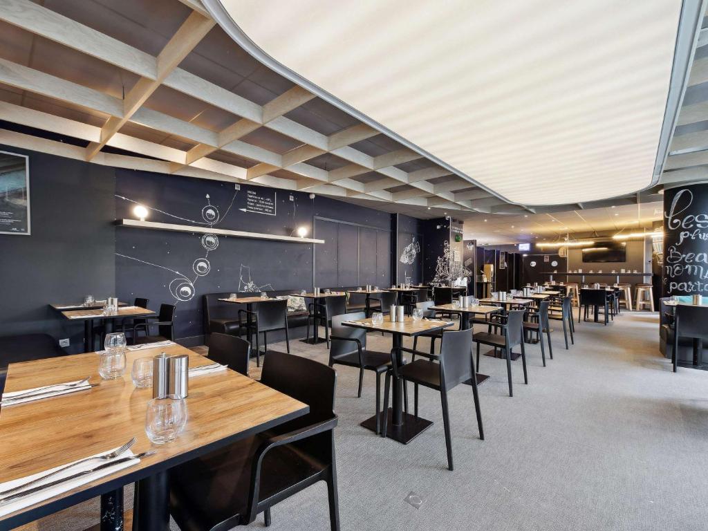 a dining room with wooden tables and chairs at ibis Styles Paris Charles de Gaulle Airport in Roissy-en-France