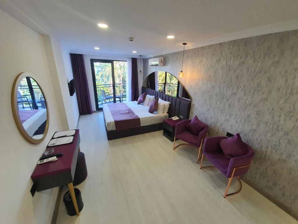 a bedroom with a bed and a table and chairs at Karikatür Bi Hotel in Alanya