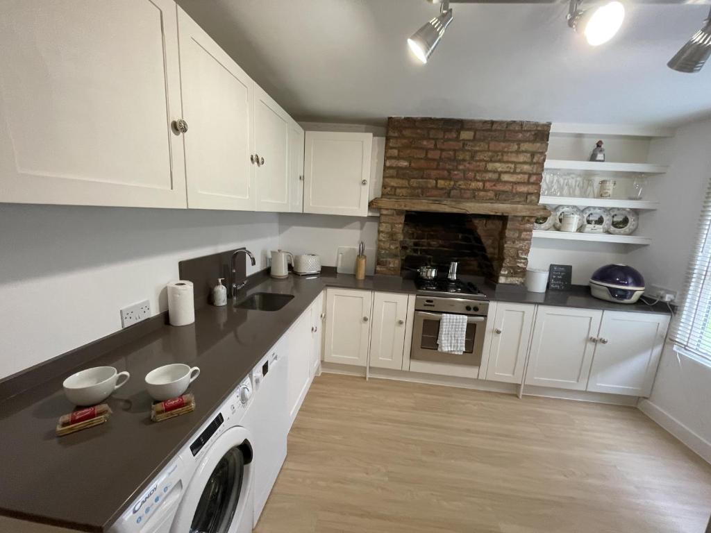 une cuisine avec des armoires blanches et un four à plaques de cuisson dans l'établissement Poplar Cottage Farnborough Kent, à Orpington