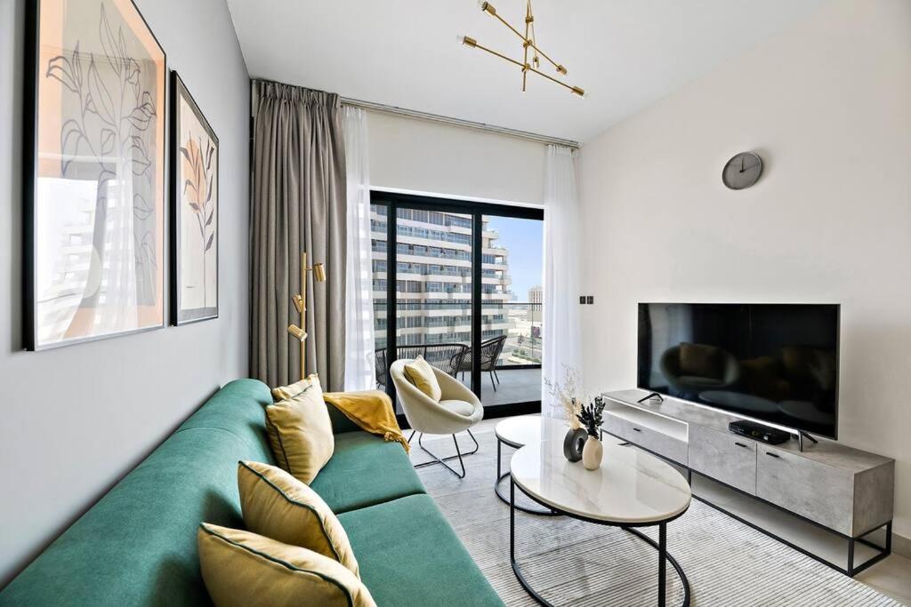 a living room with a green couch and a tv at StoneTree - Modern 1BR in Binghatti Creek in Dubai