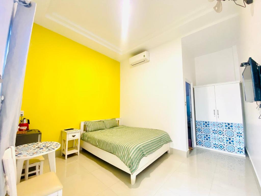 a bedroom with a bed and a yellow wall at Homestay BONO Mũi Né in Phan Thiet