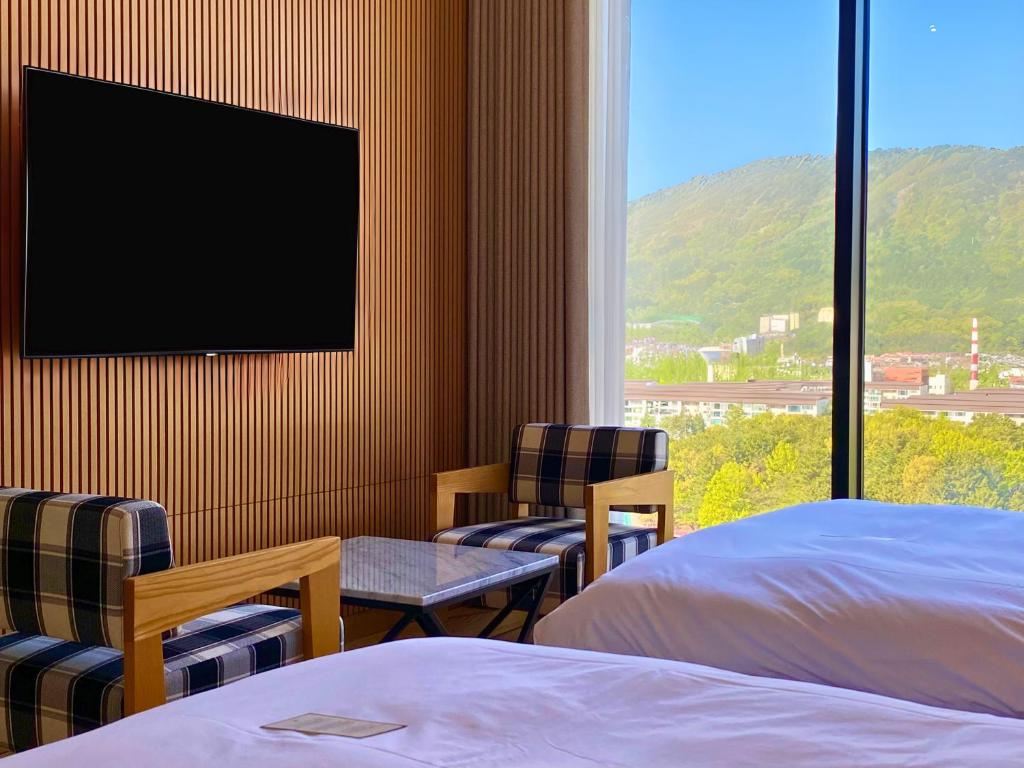 a bedroom with a bed and two chairs and a television at Hotel Avenue in Changwon