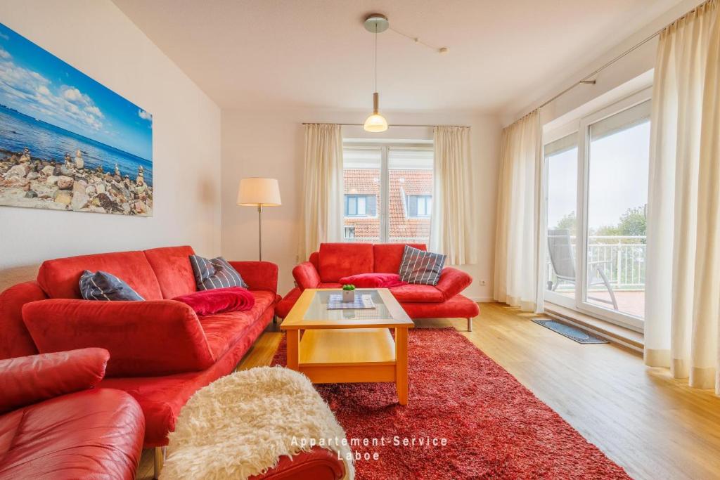 - un salon avec deux canapés rouges et une table dans l'établissement Villa Fördestrand W06, à Laboe