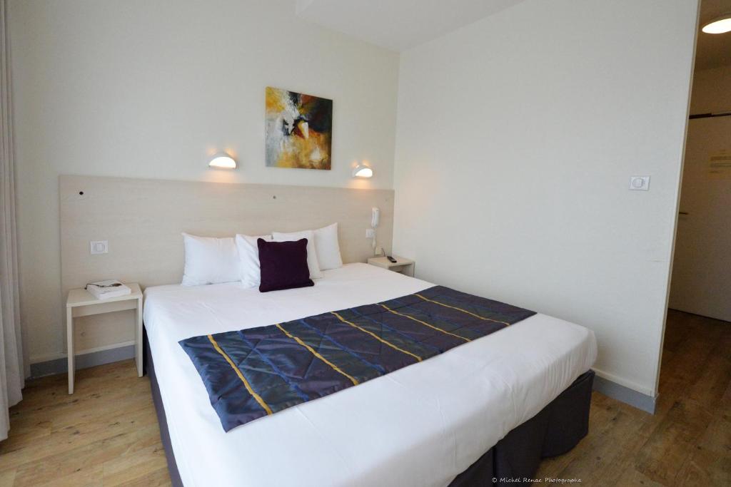 um quarto com uma grande cama branca num quarto em Logis Le Gavrinis em Baden