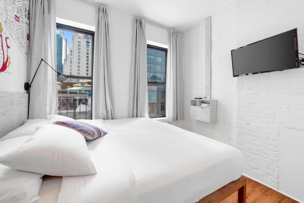a white bedroom with a large white bed and windows at BeHome by LuxUrban in New York